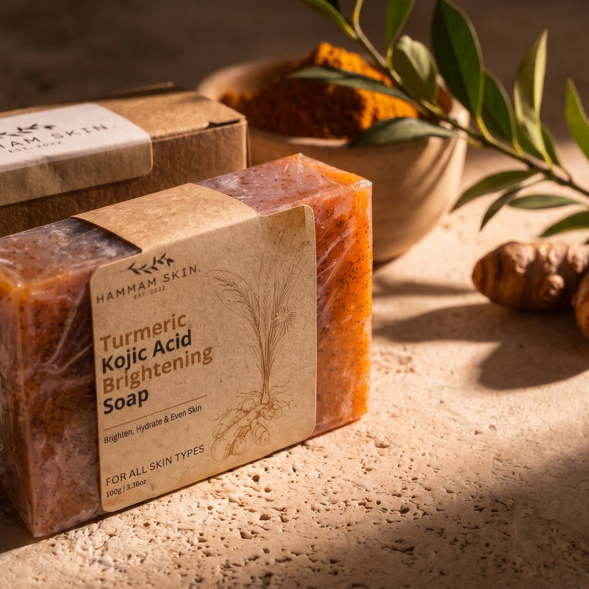 Hammam Skin turmeric and kojic acid brightening soap bar with exfoliating particles on a textured stone surface.
